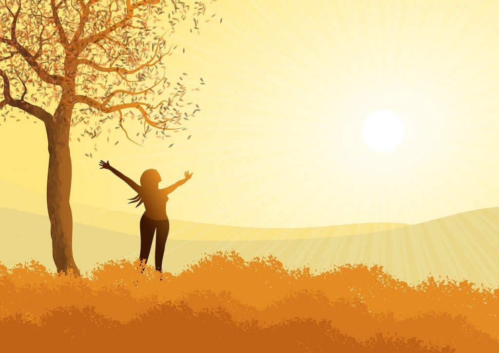Un arbre, un lever de soleil, une femme qui ouvre les bras. Les couleurs sont jaune et orangés, une impression de sérénité et de nouveau souffle se dégage